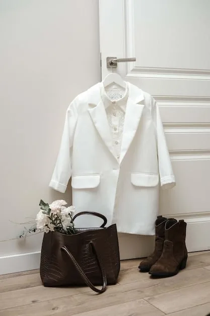 A minimalist wardrobe showcasing carefully selected timeless pieces, including a classic trench coat, a white linen blouse, dark wash denim jeans, and a pair of leather ankle boots. The image focuses on sustainable and versatile fashion choices.
