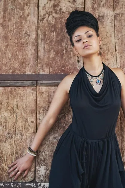A stylish woman is wearing a simple black dress and accessorizing with layered gold necklaces, a classic leather handbag, and sleek ankle boots. The accessories elevate the simple dress, creating a chic and polished casual look.