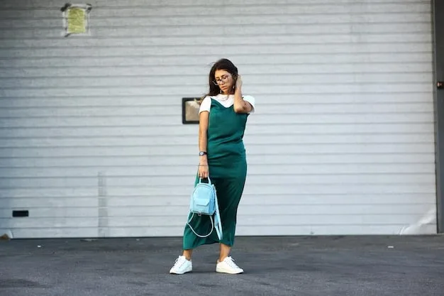 A woman wearing a navy blue jumpsuit, white sneakers, and a crossbody bag. She is smiling and holding a coffee cup, showcasing a stylish and comfortable athleisure outfit perfect for everyday activities.