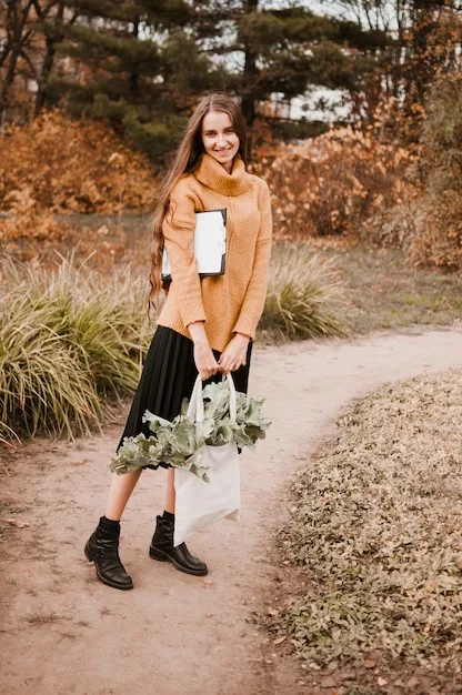 A woman wearing black leggings, a long tunic sweater, and white sneakers, carrying a stylish tote bag. The setting is a coffee shop, emphasizing the casual yet put-together nature of the outfit.