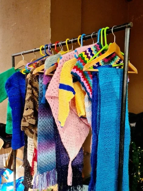 A close-up shot of a rack of colorful and diverse clothing items in a thrift store, with a focus on textures like lace, corduroy, and denim. The image captures the organized chaos of thrift store shopping, with various styles and patterns visible.