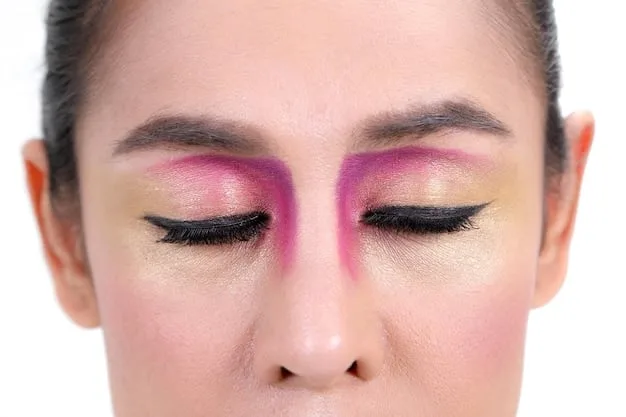 An eye with eyeshadow application, highlighting different blending zones (crease, outer corner, lid) with arrows indicating the direction of blending strokes. The image demonstrates how to achieve a smooth gradient effect.