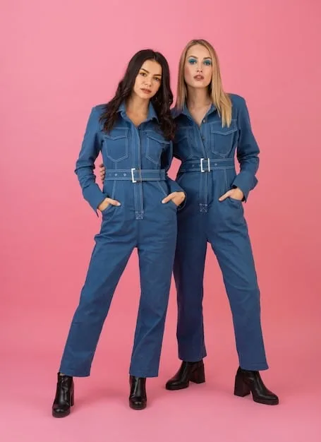 Two people standing side-by-side, both wearing the same style of jumpsuit in different colors. The jumpsuits are simple, functional, and made from durable material. The image highlights the idea of shared styles and breaking down gendered clothing categories.