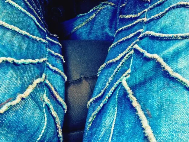 A close-up shot of a garment made from upcycled denim at NYFW 2024, highlighting the intricate patchwork and innovative design that transforms discarded material into high fashion.