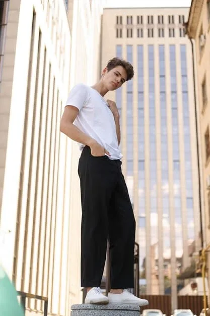 A young person confidently posing in a minimalist, oversized gender-neutral outfit, perhaps a matching top and bottom set in a neutral tone, against a clean, modern backdrop. The focus is on the comfort, effortless style, and lack of traditional gender markers in the clothing.