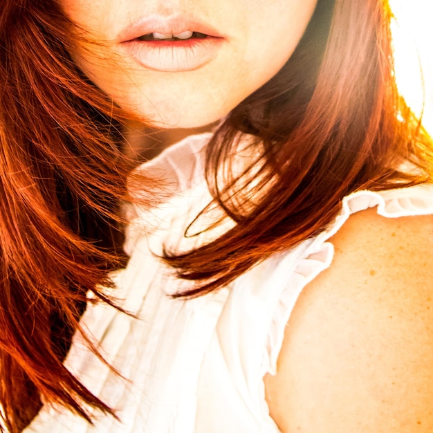 A close-up of a woman's hair showcasing a rich brunette shade with subtle caramel highlights. The hair is styled in loose waves, and the background is blurred to emphasize the hair color.