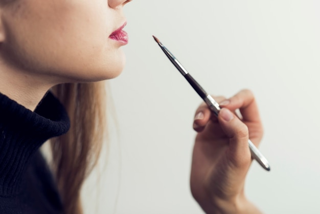A makeup artist carefully applying lip liner to a model's lips. The focus is on the precision and how the lip liner defines the shape of the lips before lipstick application.