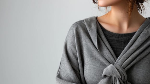 A close-up shot of a woman's torso showcasing strategic layering: a basic gray t-shirt layered underneath a slightly unbuttoned chambray shirt, topped with a lightweight olive green bomber jacket. The focus is on the textures and colors complementing each other, highlighting the effortless and stylish dimension added by layering different pieces.