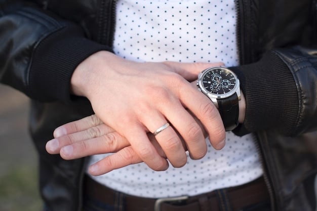 A close-up shot of a man's wrist showcasing a stylish watch paired with a simple, elegant bracelet. The focus is on the details: the watch has a classic design with a dark leather strap, while the bracelet is a thin, silver chain. The background is intentionally blurred to keep the emphasis on the accessories.