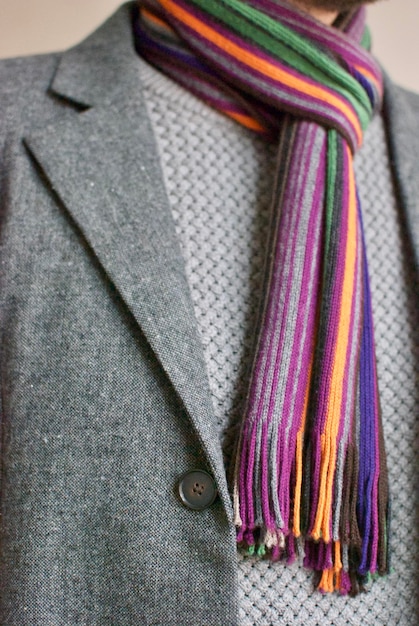 A close-up shot of different types of scarves, including silk, wool, and cotton, each styled differently: one as a neck scarf, one tied to a handbag, and one draped over the shoulders.