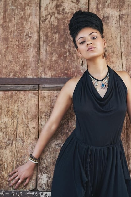 A stylish woman is wearing a simple black dress and accessorizing with layered gold necklaces, a classic leather handbag, and sleek ankle boots. The accessories elevate the simple dress, creating a chic and polished casual look.