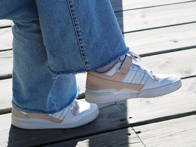 A close-up shot of a person's feet wearing white leather sneakers with blue jeans and a casual t-shirt. The background is a blurred urban setting, showcasing the sneakers in a real-world environment.