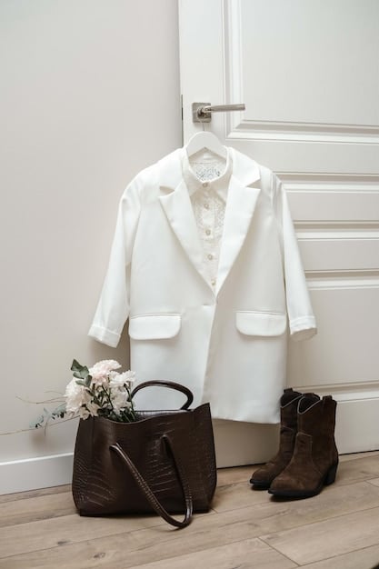 A minimalist wardrobe showcasing carefully selected timeless pieces, including a classic trench coat, a white linen blouse, dark wash denim jeans, and a pair of leather ankle boots. The image focuses on sustainable and versatile fashion choices.