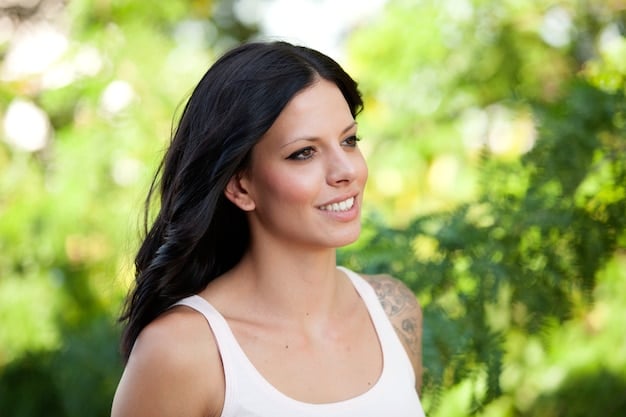 A woman with cool skin tones and dark brunette hair smiles softly. The background is a natural outdoor setting.