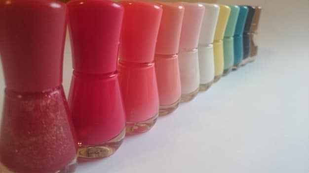 A selection of nail polishes in earthy tones, including moss green, terracotta, and sandy beige. The bottles are arranged to showcase the natural and calming palette.