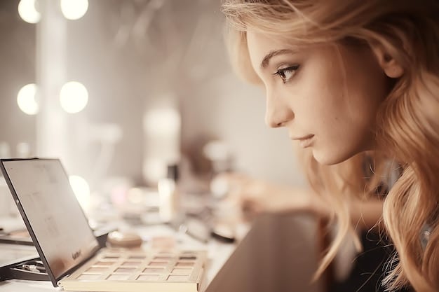 A woman with soft, natural eye makeup using brown eyeshadow and a thin line of eyeliner. The background is a well-lit makeup vanity.