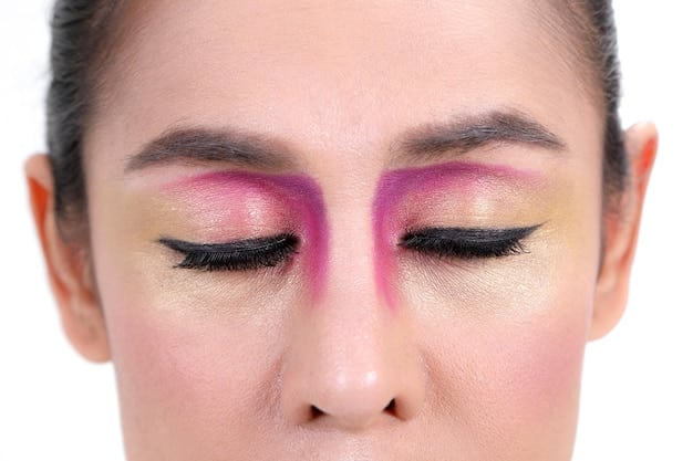 An eye with eyeshadow application, highlighting different blending zones (crease, outer corner, lid) with arrows indicating the direction of blending strokes. The image demonstrates how to achieve a smooth gradient effect.
