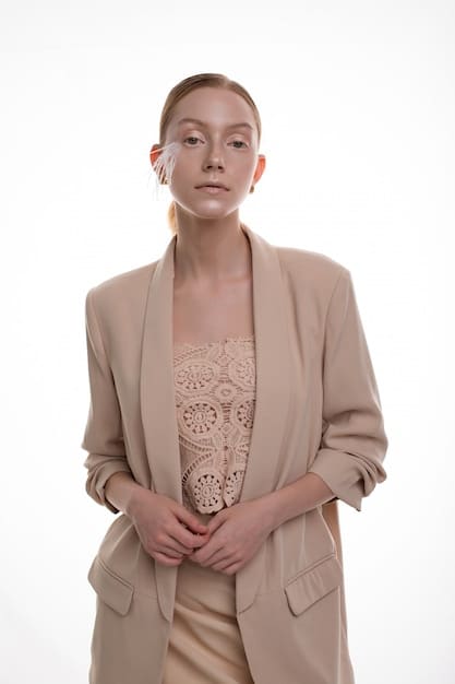 A close-up shot of a person wearing a tailored, oversized blazer in a neutral color, paired with a simple white t-shirt and dark jeans. The focus is on the blazer's fit and fabric, highlighting its versatility and sophisticated yet casual appeal.