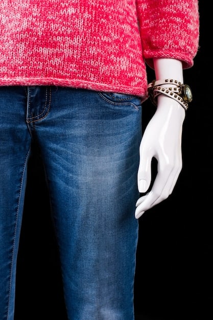 A close-up shot of various styles of low-rise jeans displayed on mannequins in a trendy boutique. The jeans range in color from light wash to dark denim, some with distressed details, others with embellishments like rhinestones or embroidery. The focus is on the low waistlines and how they are styled with different tops and accessories to create modern Y2K-inspired looks.