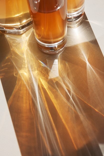 A side-by-side comparison of dark amber perfume bottles versus clear glass bottles, highlighting their ability to block light.