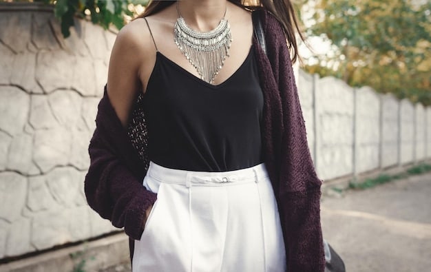 Close-up of a woman wearing a simple white Shein t-shirt accessorized with a layered silver necklaces and delicate silver rings. The background is blurred, focusing on the jewelry details.