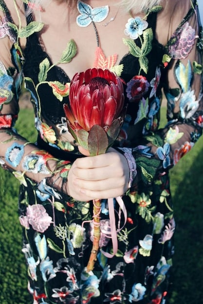A maximalist outfit featuring a mix of clashing floral and geometric patterns, bold colors like electric blue and fuchsia, layered accessories including oversized chunky jewelry and a statement hat, worn confidently by a model on a vibrant city street.