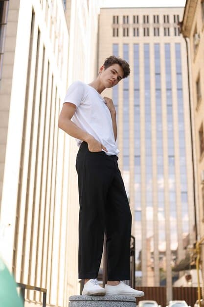 A young person confidently posing in a minimalist, oversized gender-neutral outfit, perhaps a matching top and bottom set in a neutral tone, against a clean, modern backdrop. The focus is on the comfort, effortless style, and lack of traditional gender markers in the clothing.